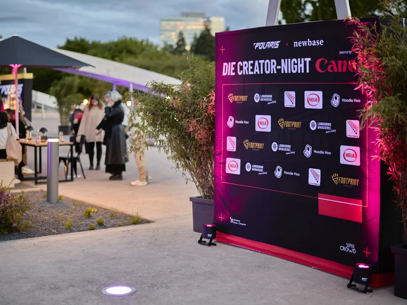 Venue glow — sponsor wall lit up in pink and purple
